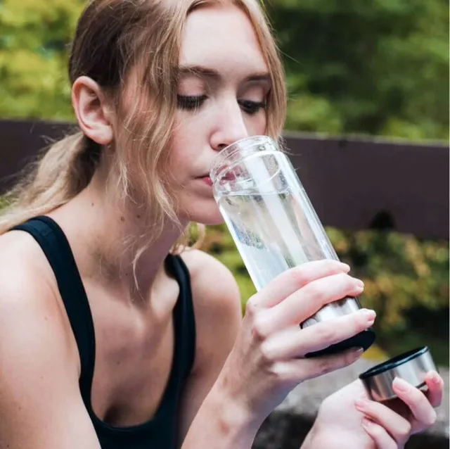 Woman drinking from the AquaFusion bottle outdoors