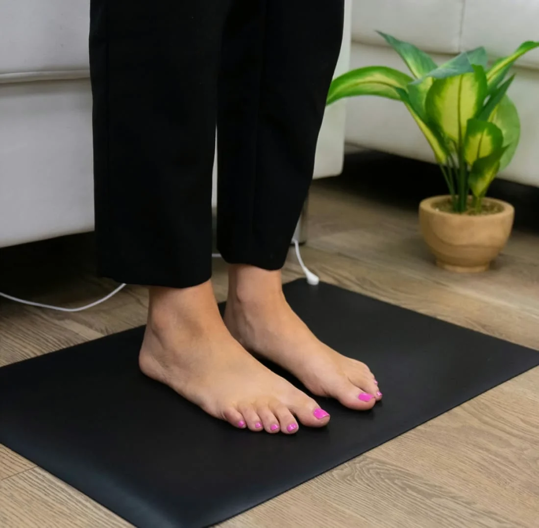 Bare feet standing on the black Bareflow grounding mat, cord visible in the background, from the seller's own product photo