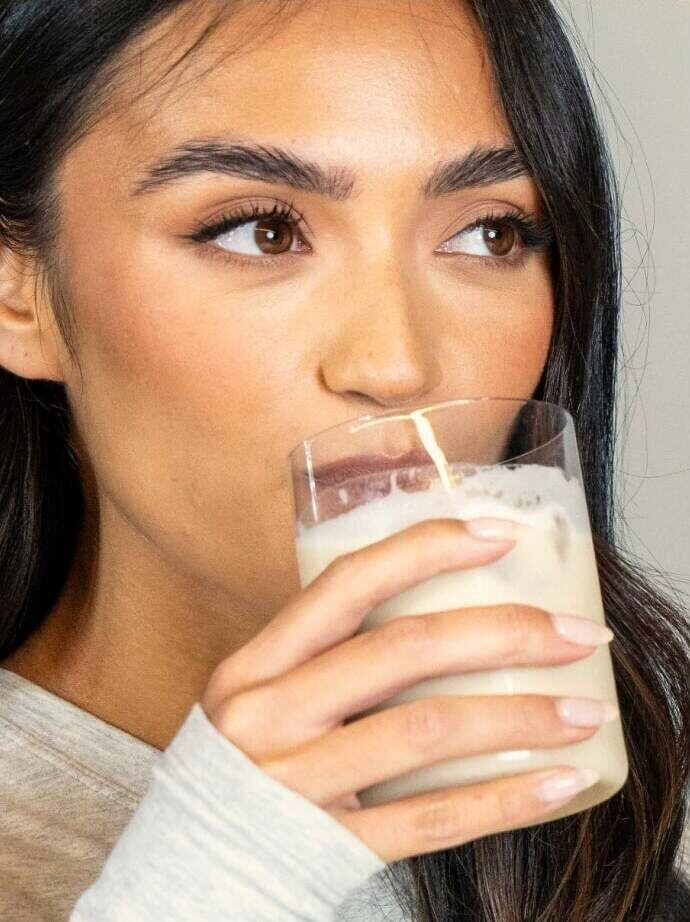 A woman drinking a glass of the prepared Free Soul shake