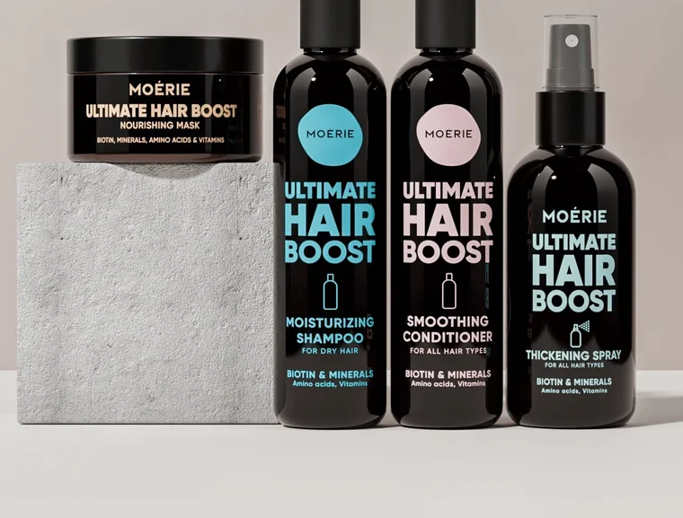 The four Moerie Ultimate Hair Boost products side by side: the nourishing mask jar, the moisturising shampoo, the smoothing conditioner and the thickening spray, all in black bottles