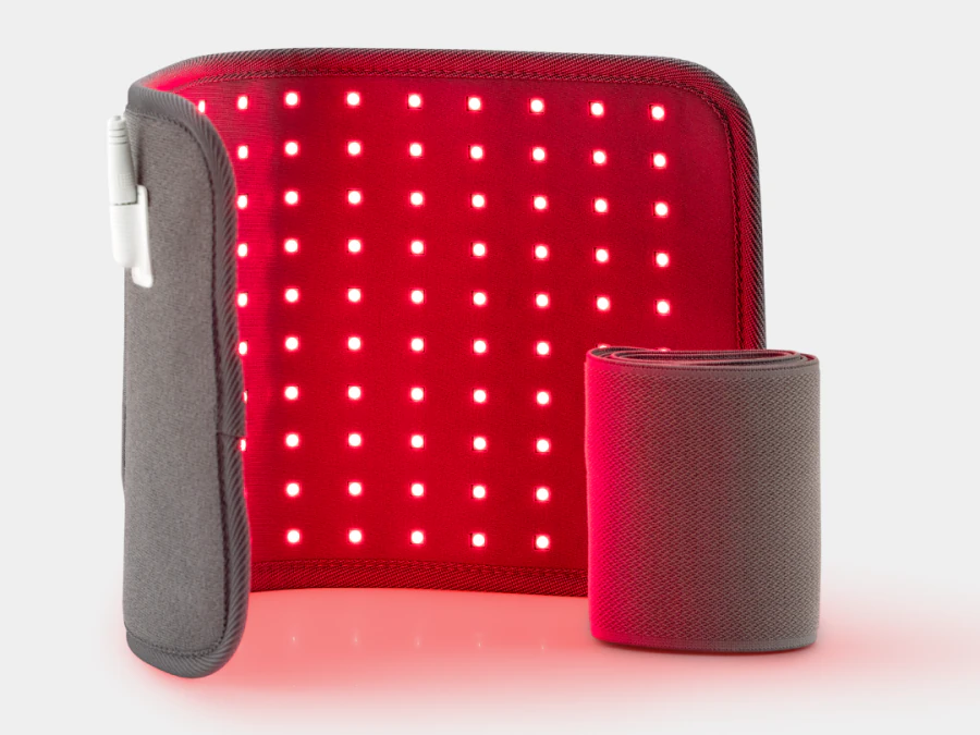 The Novaa Light Pad standing upright with its red LED grid switched on, the grey outer shell folded to the left with the cable tucked in, and its rolled strap beside it