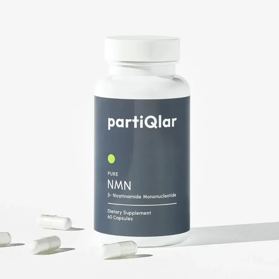 Flacone di PartiQlar Pure NMN fotografato da partiQlar: flacone bianco con etichetta ardesia che riporta PURE NMN, beta-nicotinammide mononucleotide, integratore alimentare, 60 capsule, con capsule sciolte accanto