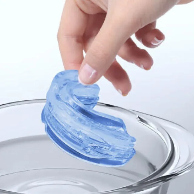 Hand dipping the SleepZee mouthpiece into a bowl of hot water to soften it