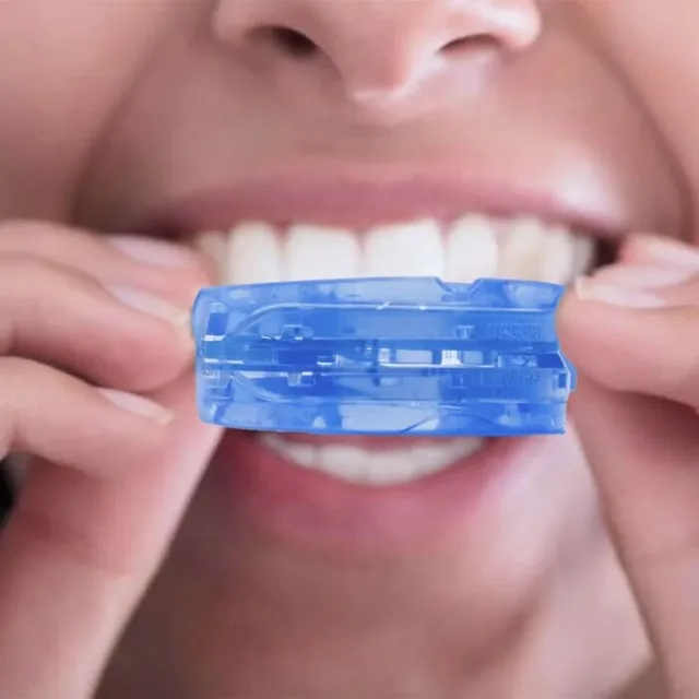 Person holding the molded mouthguard in front of their teeth, from SleepZee's fitting photos